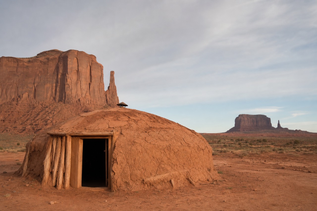 A traditional Navajo hogan, a round earth-and-timber dwelling, on the red desert floor of Monument Valley