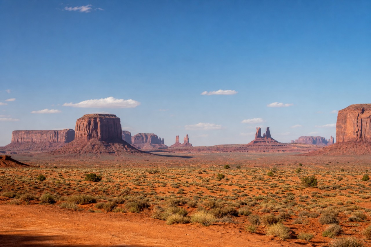 Wide panoramic view of the red sandstone buttes and mesas of Monument Valley rising from the desert floor