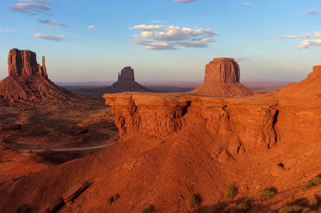 John Ford Point promontory jutting over the Monument Valley floor with sandstone buttes beyond in late afternoon light