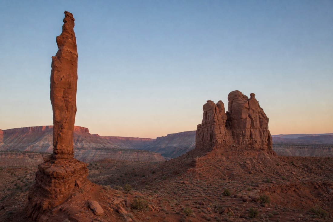 The slender Totem Pole spire and the Yei Bi Chei formation standing alone in the empty backcountry at dawn