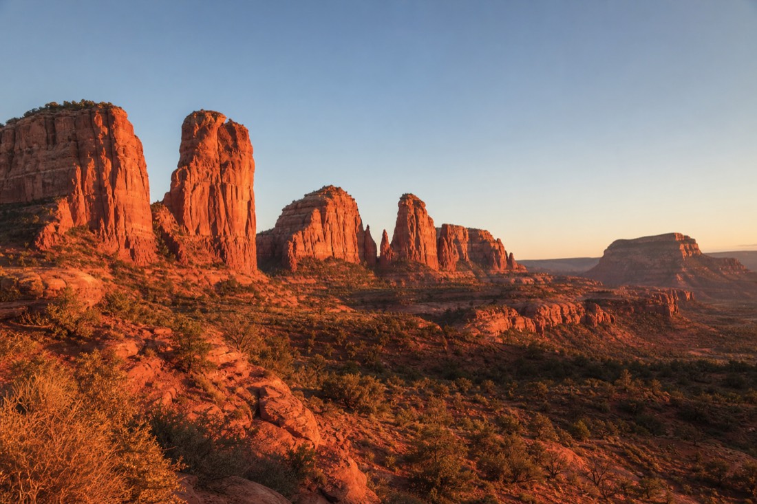 Deep orange-red sandstone buttes glowing under a low sun in the last hour of golden-hour light before sunset