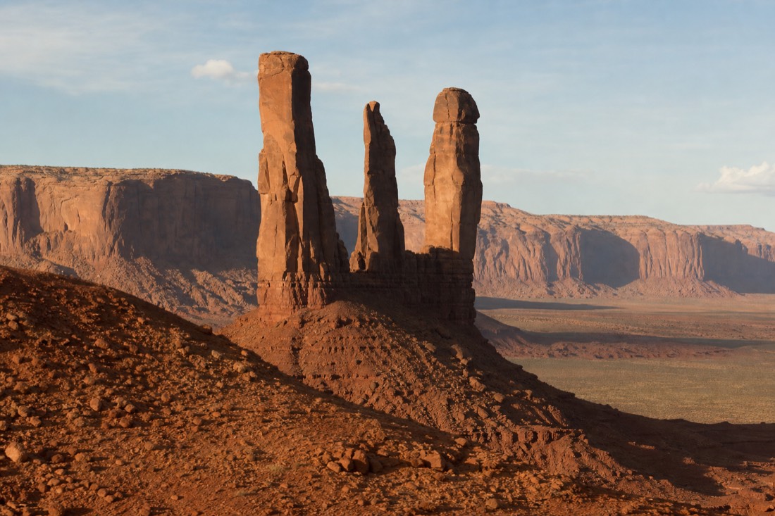 The Three Sisters, a cluster of slender sandstone spires rising from the desert floor of Monument Valley