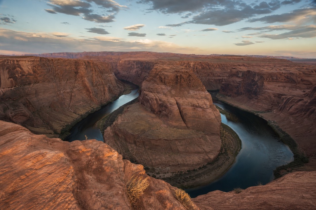 Horseshoe Bend's curving green river gorge under a wide desert sky