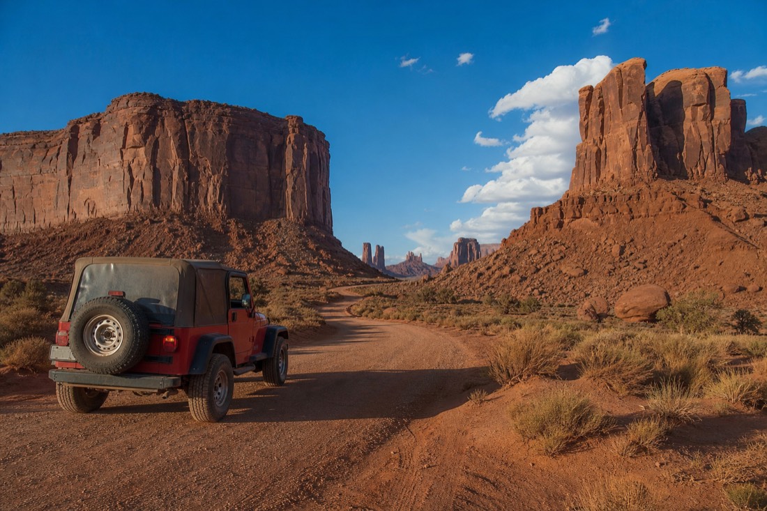 A Navajo jeep on the scenic loop road with buttes rising on either side