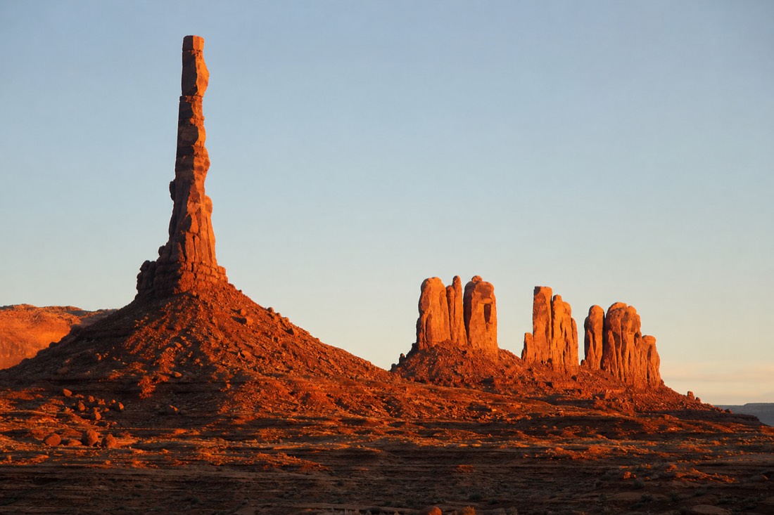 The Totem Pole spire and Yei Bi Chei formations glowing at dawn over the desert floor